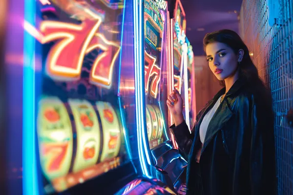 A glamorous woman holding casino chips in a neon-lit environment, representing the premium online casino atmosphere of 777JAYA.